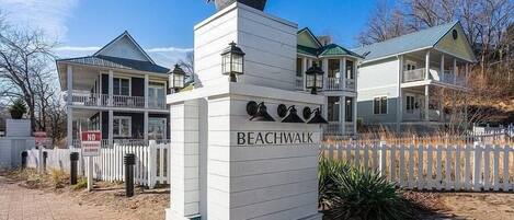 A white building with a sign reading "BEACHWALK" and a white picket fence.