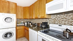 A kitchen with wooden cabinets, a microwave, a dishwasher, a stove, and a sink.