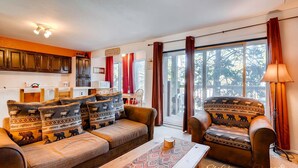 A cozy living room with a sofa and armchair, a coffee table, and a view of the outdoors through large windows. - Adorable Condo, Walking Distance To Everything. Including Pool/Hot Tub IC4 (Breckenridge)