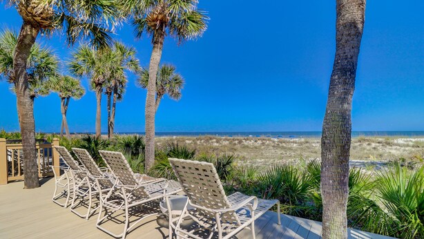 Eine Terrasse mit Liegestühlen mit Blick auf einen Strand.