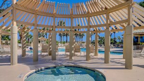 Ein Poolbereich mit einem runden Whirlpool, Liegestühlen und einer Pergola.