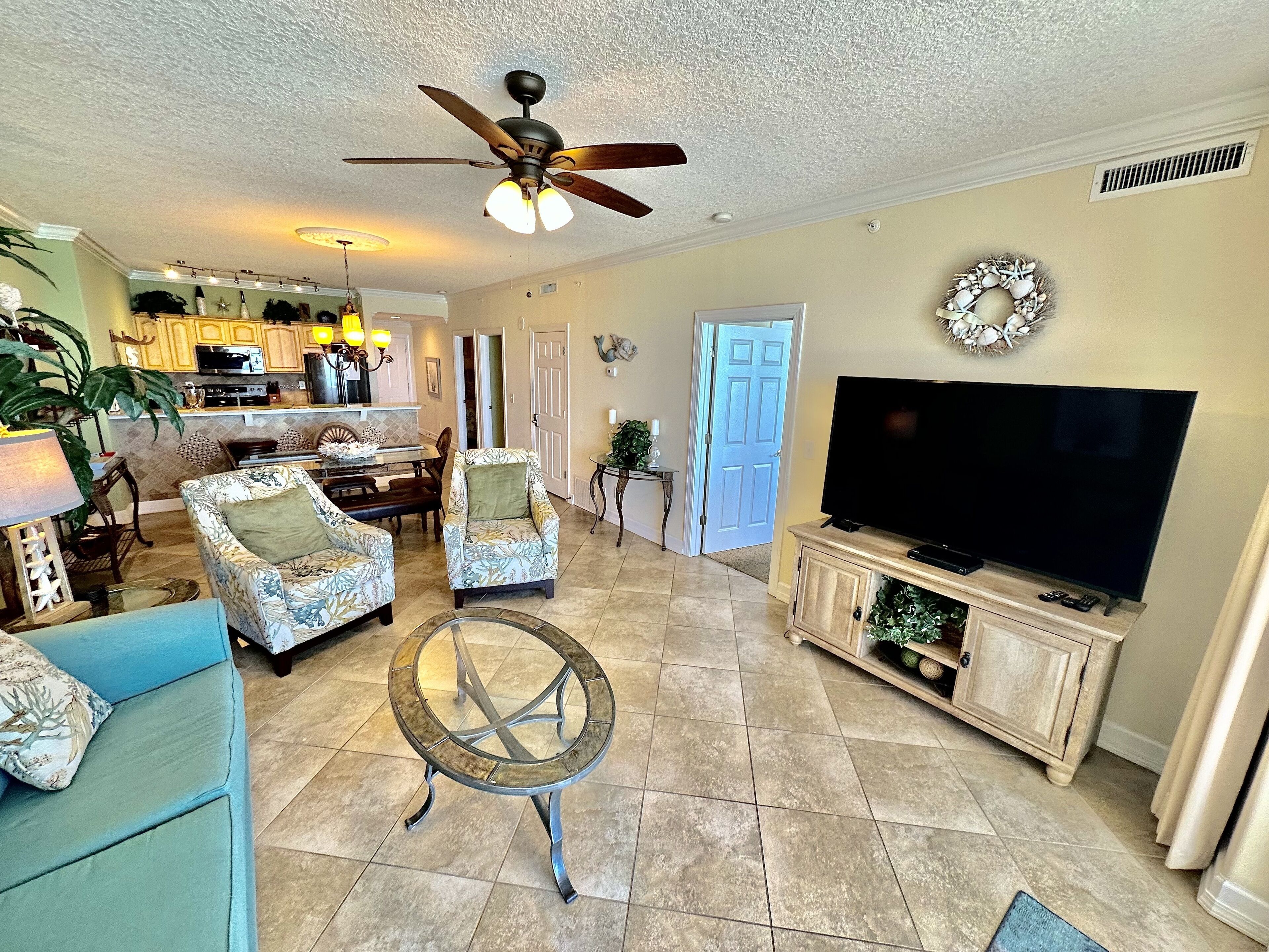 A spacious living room with a ceiling fan, a television, and a dining area with chairs and a table.