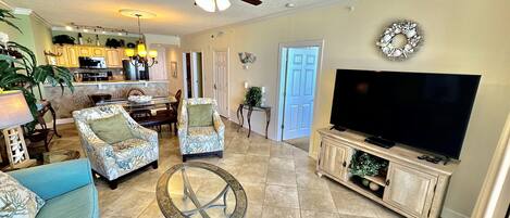 A spacious living room with a ceiling fan, a television, and a dining area with chairs and a table.