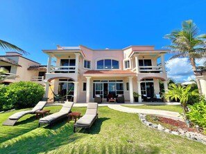 A two-story house with a large front porch, multiple windows, and a well-maintained lawn with lounge chairs.