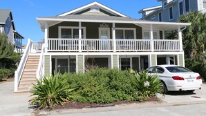 A two-story house with a balcony, a staircase, and a car parked in front.