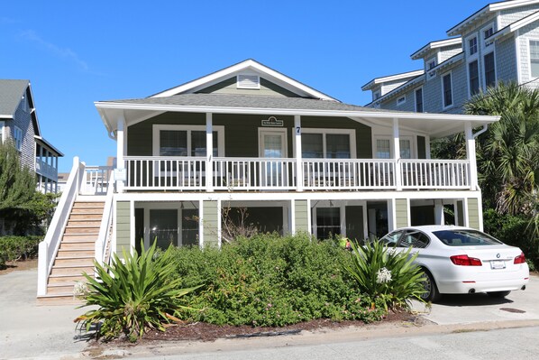 A two-story house with a balcony, a staircase, and a car parked in front.