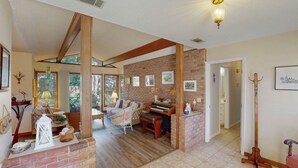 A spacious living area with a piano, a fireplace, and a view of the outdoors.