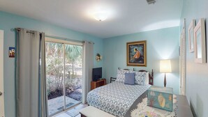 A bedroom with a bed, a TV, a lamp, and a painting on the wall.