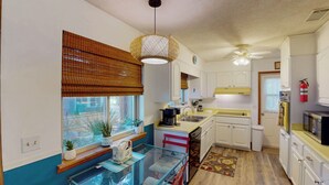 A compact kitchen with a window, a ceiling fan, and a microwave.