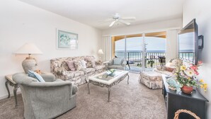 A living room with a sofa, armchair, and coffee table, a television, and a balcony with a view. - ☀️Across St from Beach-Spacious Balcony-Gulf Views-Complex Pool-2BR Ciboney 4003 (Miramar Beach)