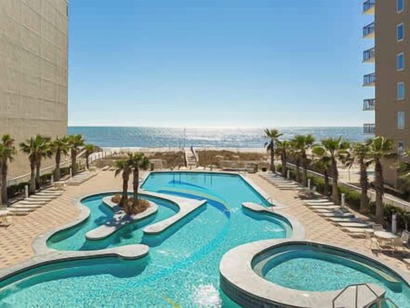 A swimming pool with a unique design, surrounded by palm trees and a view of the ocean.