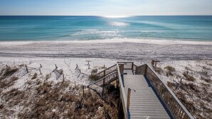 A wooden boardwalk leading to a beach with a clear view of the ocean.