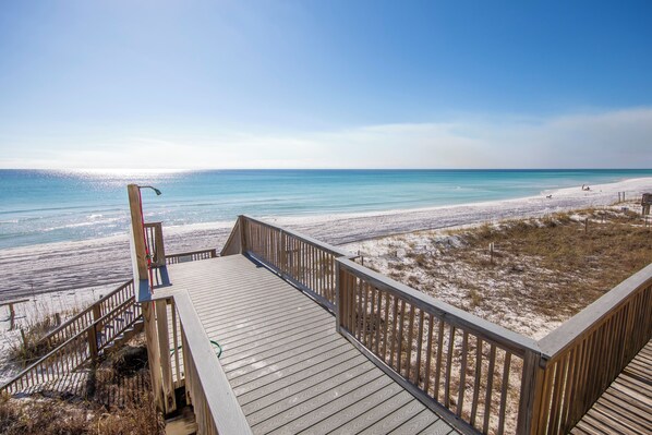 A wooden boardwalk leading to a beach with clear skies.