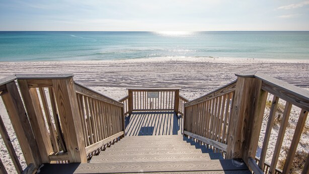 A wooden staircase leading to a beach with a clear view of the ocean.