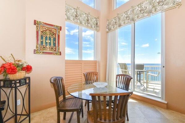 Uma sala de jantar com mesa de vidro, cadeiras de madeira e um painel decorativo na parede.