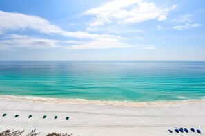 A beach with rows of beach chairs and umbrellas, a clear sky, and calm sea. - Two-story beachfront penthouse w/ extra-large balcony! 🌅 (Destin)