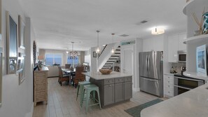 Een moderne keuken met een centraal kookeiland, roestvrijstalen apparatuur en een eethoek met uitzicht.