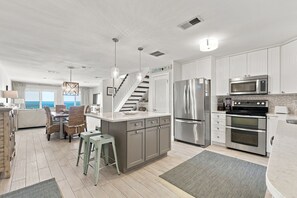 A modern kitchen with stainless steel appliances, a central island, and a view to the ocean.