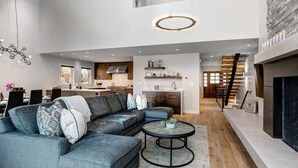 Uma sala de estar ampla com sofá seccional, mesa de centro redonda e lareira.