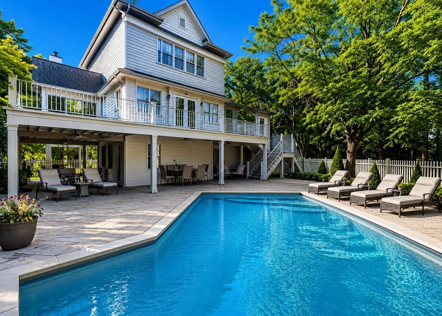 A two-story house with a swimming pool, outdoor seating, and a covered patio area.