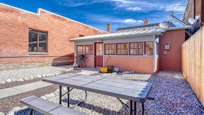 Un jardin avec une table de patio, un barbecue et un abri de jardin.