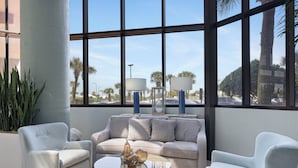 A modern living room with a sofa, two armchairs, a coffee table, and a view through large windows.