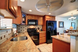A kitchen with wooden cabinets, a microwave, stove, refrigerator, and a sink.