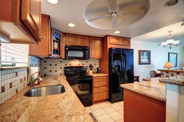 A kitchen with wooden cabinets, a microwave, stove, refrigerator, and a sink.