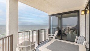 A balcony with a view of the ocean, a table, and two chairs. - Broadmoor 901 by Liquid Life (Orange Beach)
