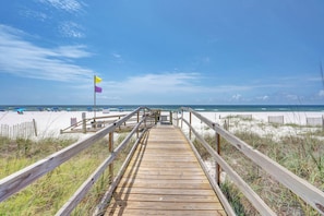 A wooden boardwalk leading to a beach with a clear sky.