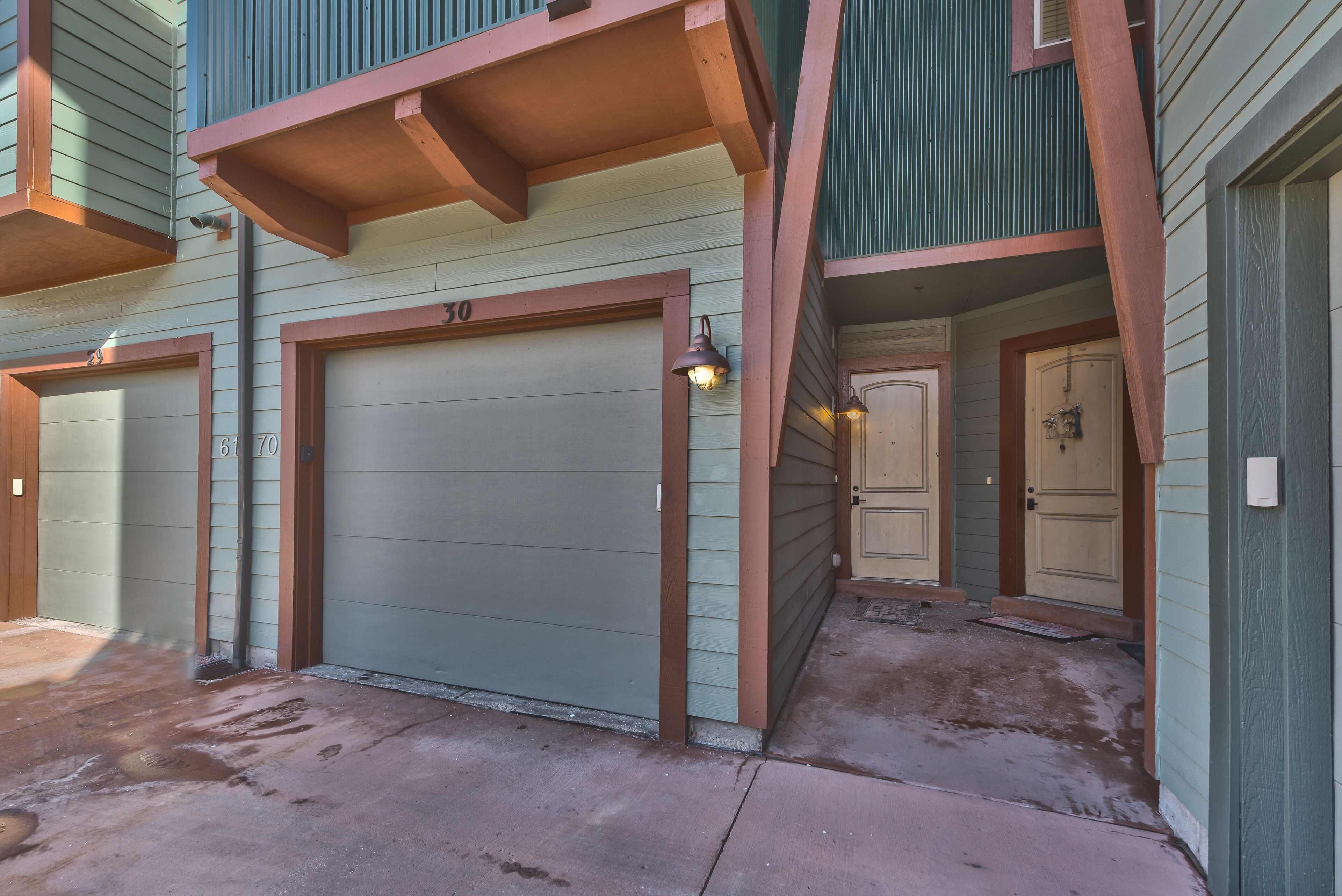 A building with a garage door, a door, and a small porch area.