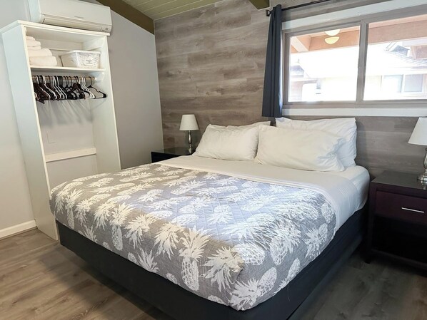 Un dormitorio con cama, armario, mesita de noche y ventana.
