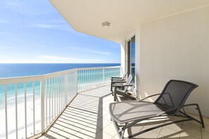 Un balcon avec vue sur l’océan, une chaise et une table.