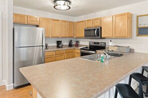 A modern kitchen with wooden cabinets, stainless steel appliances, and a large island with bar stools.
