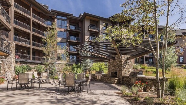 Un edificio de varios pisos con terraza al aire libre y un patio cubierto.