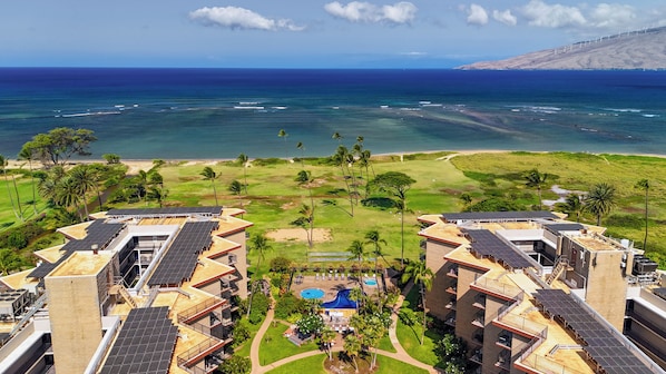 A resort with multiple buildings, a swimming pool, and a view of the ocean.
