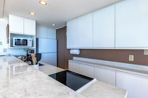 A modern kitchen with white cabinets, a built-in microwave, a stove, and a countertop with utensils.