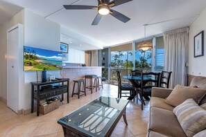 A modern living room with a glass coffee table, a sofa, and a TV mounted on the wall.
