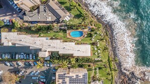 An aerial view of a coastal hotel with a swimming pool, parking area, and ocean view. - Island Paradise Found: Comfort and Oceanfront Views at Kamaole Nalu #404 (Kihei)