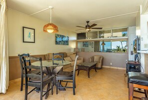 A spacious living area with a dining table, chairs, a sofa, and a ceiling fan.