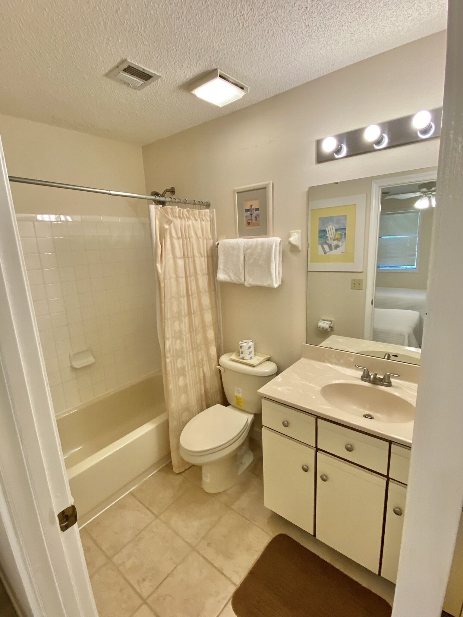 A bathroom with a shower, toilet, sink, and vanity.