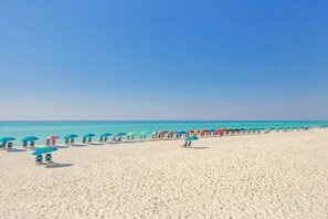 Een strand met rijen parasols en strandstoelen.