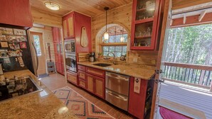 A kitchen with wooden cabinets, stainless steel appliances, and a large window. - Monarch Crest Chalet- Sauna and Pet Friendly (Salida)