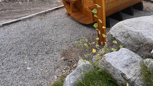 A wooden cabin with a curved roof, situated on a gravel path with a forest backdrop. - Monarch Crest Chalet- Sauna and Pet Friendly (Salida)