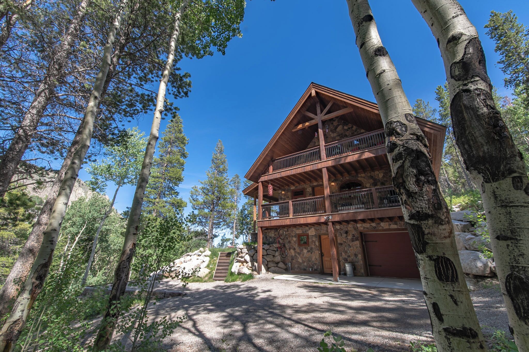 A lodge with a stone facade, wooden balcony, and a stone staircase leading up to the entrance.