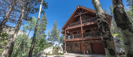 A lodge with a stone facade, wooden balcony, and a stone staircase leading up to the entrance.