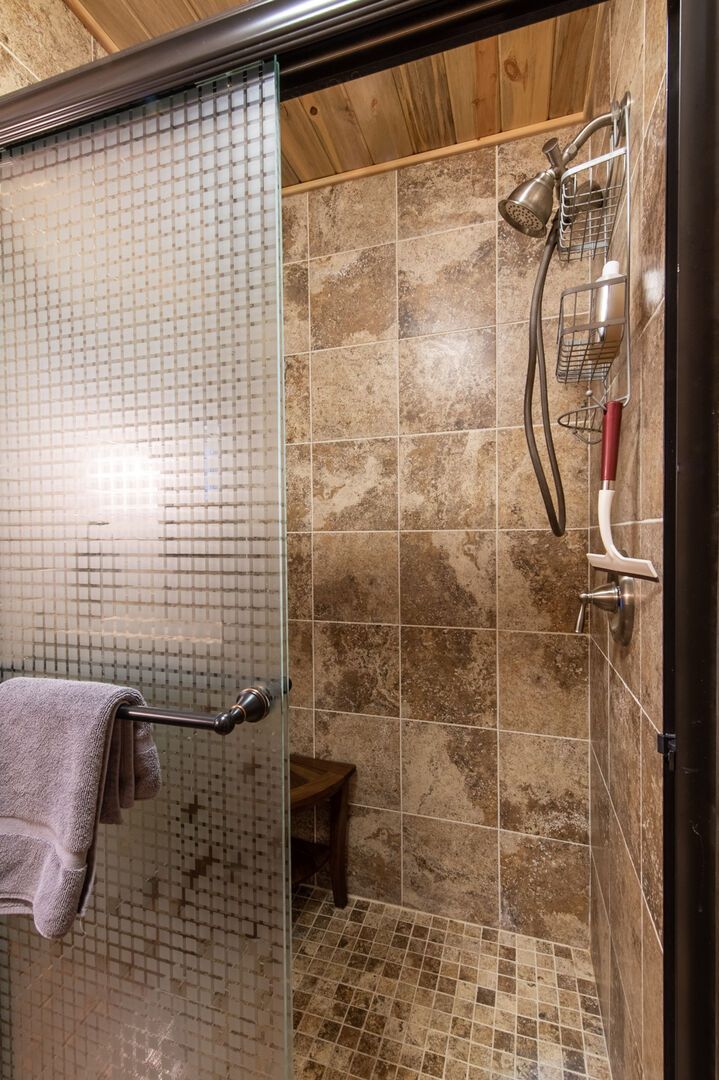 A shower with a glass door, tiled walls, and a towel rack.