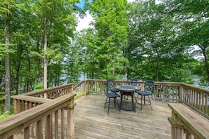 Relax on the deck surrounded by lush greenery and a body of water.