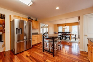 A modern kitchen with stainless steel appliances, wooden cabinets, and a central island with stools.