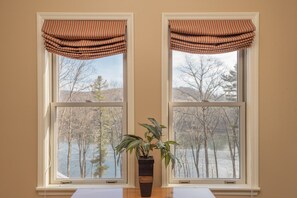 Enjoy a serene view of the surrounding landscape from the room's two windows, featuring a potted plant and a natural outdoor setting.